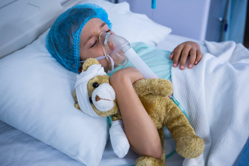 Patient with oxygen mask relaxing on bed in ward at hospital Patient wearing an oxygen mask resting in a hospital ward